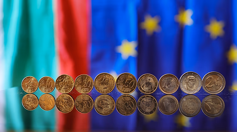 Nouvelles pièces en euros avec des symboles bulgares reflétés dans un tableau sur fond de drapeau bulgare et européen, à Sofia, le 30 décembre 2025