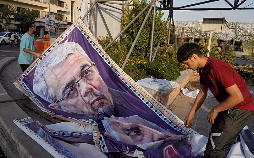Des ouvriers préparent un portrait du défunt chef d'état-major de l'armée iranienne, le général Mohammad Hossein Bagheri, tué lors d'une frappe israélienne en juin, à Téhéran, le 22 septembre 2025.