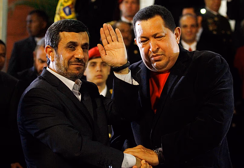 DOSSIER : Le président iranien Mahmoud Ahmadinejad salue alors qu'il serre la main du président vénézuélien Hugo Chavez au palais présidentiel de Miraflores à Caracas, le 22 juin 2012.