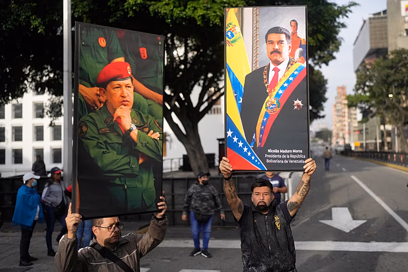Des partisans du gouvernement affichent des affiches du président vénézuélien Nicolás Maduro, à droite, et de l'ancien président Hugo Chávez dans le centre-ville de Caracas, au Venezuela, le samedi 3 janvier 2026.