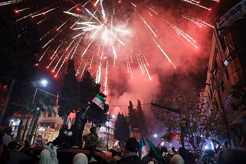 Fireworks illuminate the sky as people fill Clock Square in Homs, 8 December, 2025