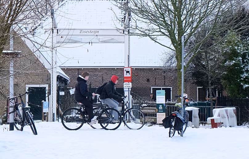 Deux jeunes Néerlandais font du vélo prudemment le long d'une piste cyclable couverte de glace près d'une ferme pour enfants dans la ville de Voorburg, le 6 janvier 2026.