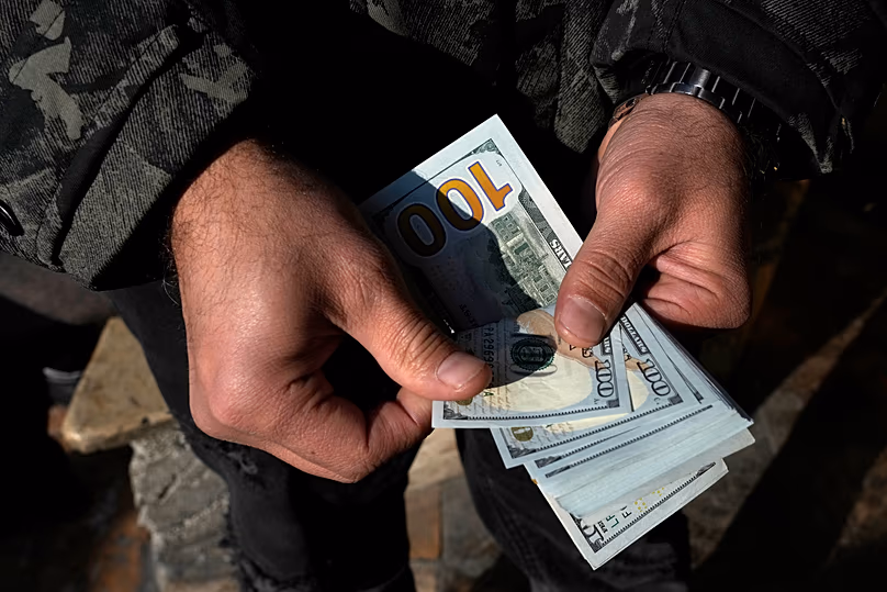 Un homme compte des dollars américains dans la rue Ferdowsi, dans le centre-ville de Téhéran, le 18 décembre 2024.