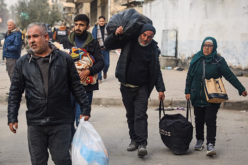 Des habitants transportent leurs affaires alors qu'ils fuient les quartiers de Cheikh Maqsoud et Achrafieh à Alep, le 8 janvier 2026.