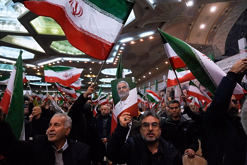 Des gens brandissent des drapeaux iraniens lors d'une cérémonie à la grande mosquée de l'Imam Khomeini à Téhéran, le 1er janvier 2026.