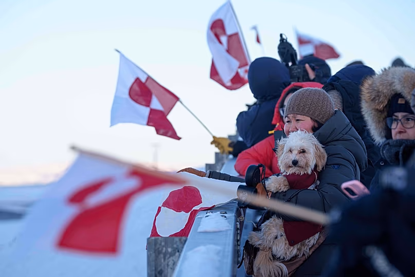 Des personnes brandissent des drapeaux nationaux pour la ministre groenlandaise des Affaires étrangères et de la Recherche, Vivian Motzfeldt, à son arrivée à l'aéroport de Nuuk, le 20 janvier 2026.