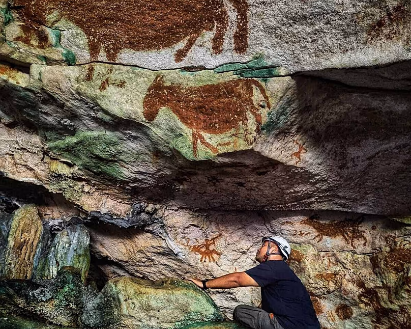 Cette image fournie par Maxime Aubert montre la scientifique Shinatria Adhityatama étudiant l'art rupestre découvert à Sulawesi, en Indonésie.