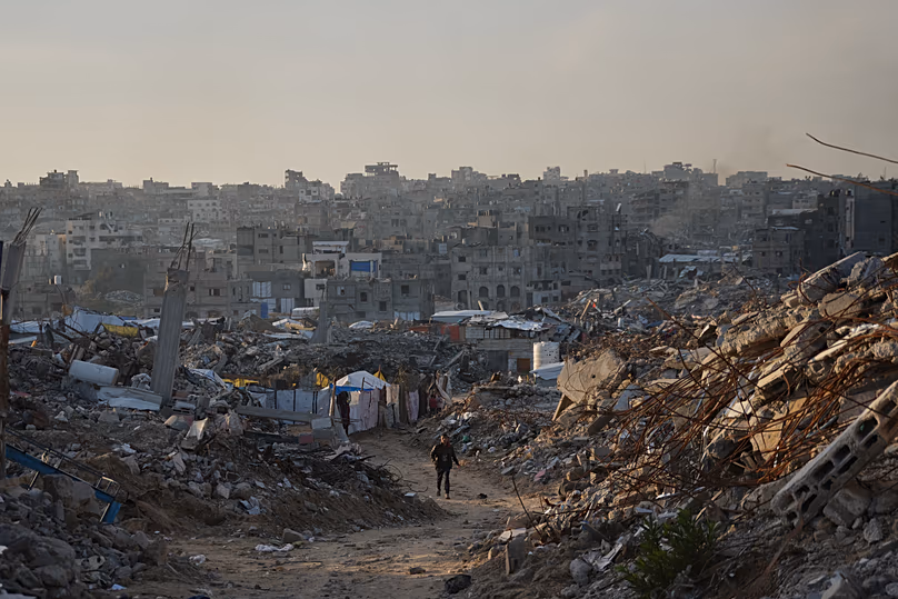 A Palestinian man walks along a road surrounded by buildings destroyed during Israeli air and ground operations in Gaza City, 30 December, 2025