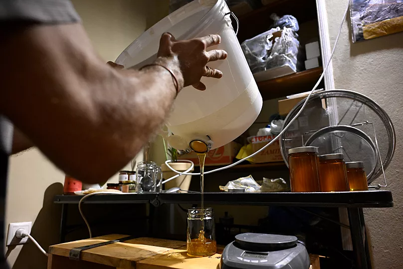 Nikos Chadjilias remplit un pot de miel dans la banlieue de Zografou à Athènes, en Grèce.