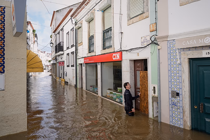 Des habitants placent des planches pour empêcher l'eau de pénétrer dans les maisons inondées après le débordement du fleuve Sado en raison de fortes pluies à Alcácer do Sal, dans le sud du Portugal, le 6 février 2026.