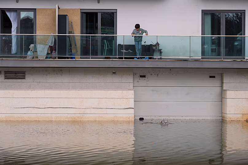 Un garçon regarde les eaux de crue après de fortes pluies à Coimbra, au Portugal, le vendredi 13 février 2026.