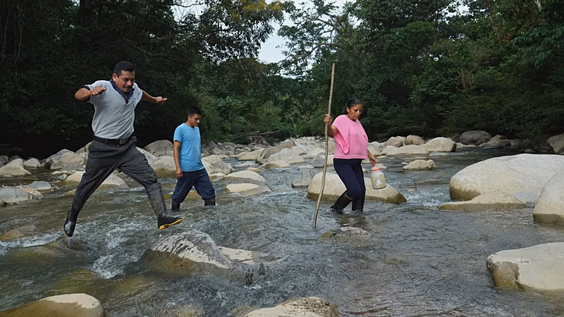 Ramon Pucha, son fils Jhoel et sa femme Marlene traversent la rivière Alto Ila lors d'une expédition à la recherche de graines indigènes à cultiver dans leur ferme, dans la région amazonienne de l'Équateur.