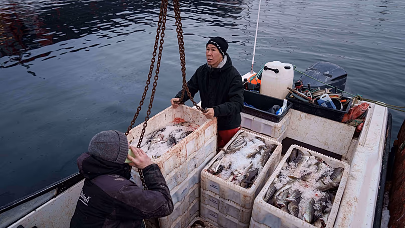 Des pêcheurs déchargent des caisses de poisson d'un bateau dans le port de Nuuk, au Groenland, le jeudi 22 janvier 2026.