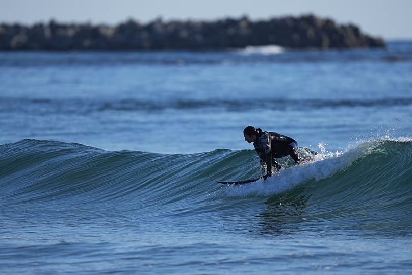 Un surfeur se prépare à surfer sur une vague sur la plage de Toyoma à Iwaki, dans le nord-est du Japon, le mardi 10 février 2026.