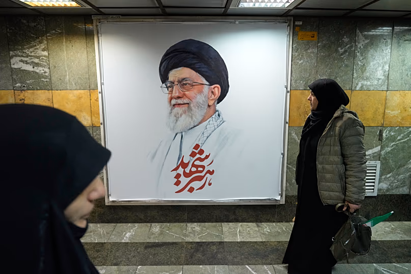 Des gens passent devant un portrait du défunt guide suprême iranien, l'ayatollah Ali Khamenei, dans une station de métro à Téhéran, le 13 mars 2026.