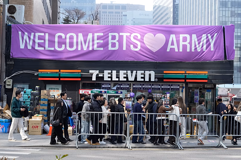 Les gens passent devant une bannière pour BTS avant un concert de retour du groupe de K-pop près de la place Gwanghwamun à Séoul, en Corée du Sud