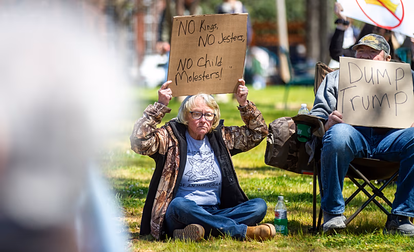 Des manifestants brandissent des pancartes lors du rassemblement « No Kings » au parc Wilson à Florence, en Alabama, le samedi 28 mars 2026.