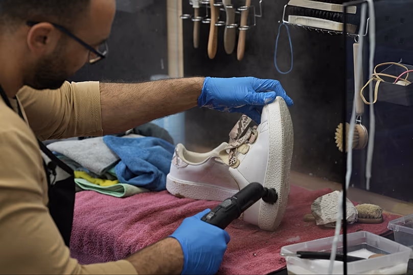 DOSSIER : Un ouvrier nettoie une chaussure d'entraînement usagée chez SneakCoeurZ, une entreprise à but non lucratif recyclant des chaussures en France, le 25 mars 2026.