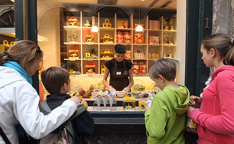 DOSSIER : Des touristes regardent une vitrine où une femme décore des œufs en chocolat pour Pâques dans une chocolaterie du centre-ville de Bruxelles, le vendredi 6 avril 2012.