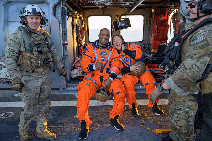 Sur cette photo fournie par la NASA, ses astronautes Victor Glover, pilote d'Artemis II, à gauche, et Christina Koch, spécialiste de la mission Artemis II, sont assis sur un Navy MH-60 Seahawk.