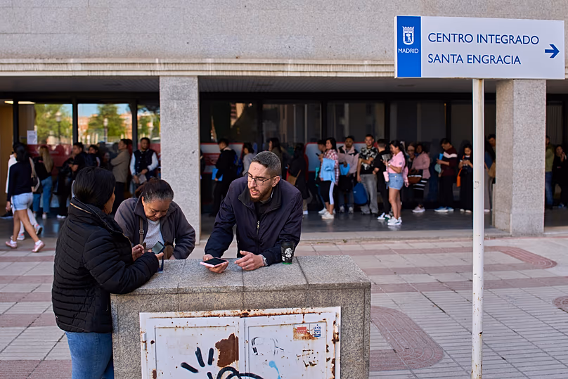 Des immigrants font la queue pour demander un certificat de transport public à Madrid, le 16 avril 2026