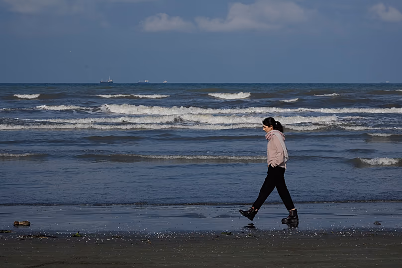 Une femme marche le long de la côte sud de la mer Caspienne, dans la ville portuaire de Bandar Anzali, le 21 décembre 2025.