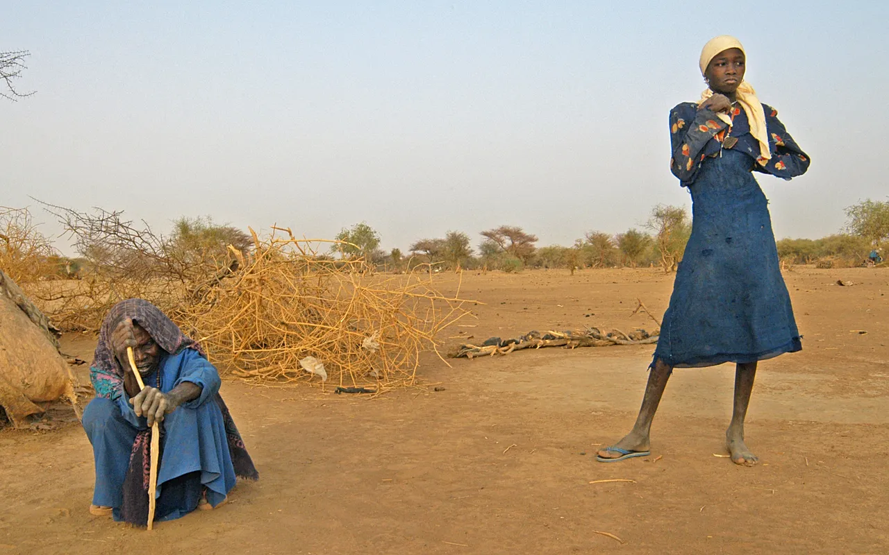 Une femme et sa petite-fille dans leur abri rudimentaire après avoir fui les combats au Darfour (2004).