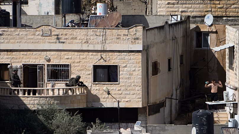 Un homme lui tient la main alors qu’il est en vue de deux soldats israéliens dans la ville de Qabatiya en Cisjordanie lors d’un raid, le jeudi 19 septembre 2024. (AP Photo/Majdi Mohammed)