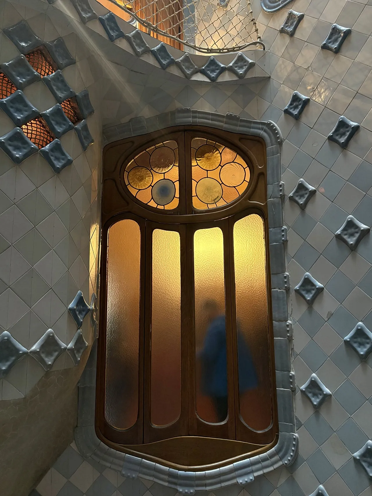 La figure se tient derrière une fenêtre donnant sur le puits de lumière central de la Casa Batllo, Barcelone, Catalogne, Espagne, 2026.