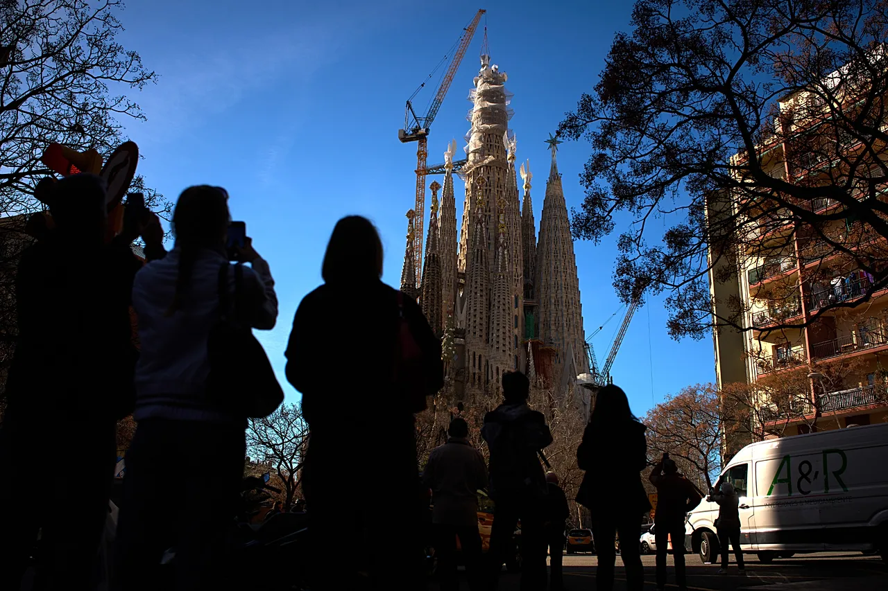 DOSSIER – Des gens regardent une grue poser la croix sur la tour de Jésus-Christ à la Sagrada Familia à Barcelone, Catalogne, Espagne, février 2026.