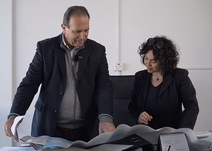 L'adjoint au maire d'Akrotiri, Giorgos Kostantinou, montre à la journaliste Monica Pinna la proximité de son village avec la base aérienne britannique d'Akrotiri.