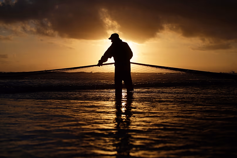 Un pêcheur portugais tire un filet de la mer sur la plage près de Lisbonne, le 6 octobre 2014.