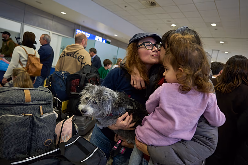 Une Grecque rapatriée avec son chien embrasse ses proches lors de leur arrivée à l'aéroport international d'Athènes Eleftherios Venizelos après avoir été évacuée d'Abu Dhabi.