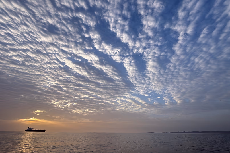 Le soleil se lève derrière un pétrolier ancré dans le détroit d'Ormuz, au large de l'île de Qeshm, en Iran, le 18 avril 2026.