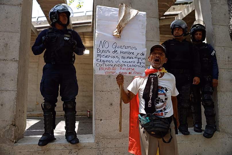 La police entoure un manifestant qui participe à une marche réclamant des salaires, des retraites et des avantages sociaux plus élevés à Caracas, le 9 avril 2026.