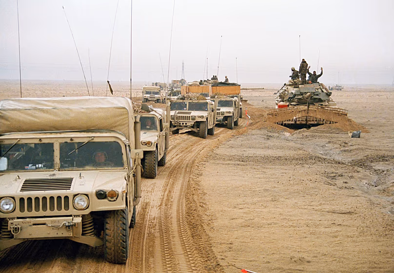 DÉPOSER. Un convoi de véhicules de la Deuxième Division des Marines des États-Unis passe devant un char au Koweït, en février 1991.