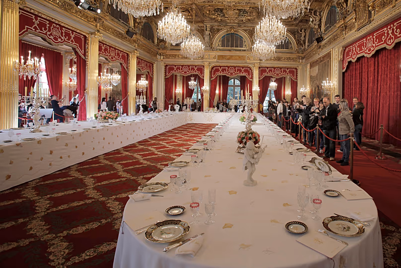 Des visiteurs regardent une table garnie d'assiettes et de verres pour des dîners officiels au palais de l'Élysée à Paris, le 15 septembre 2012