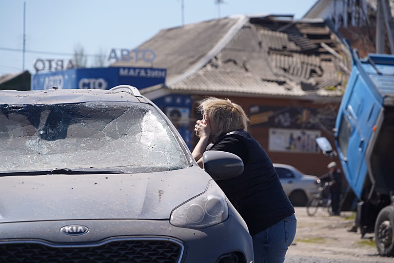 Une femme pleure en regardant un conducteur mort dans une voiture endommagée suite à une attaque de missile russe à Merefa, le 4 mai 2026.