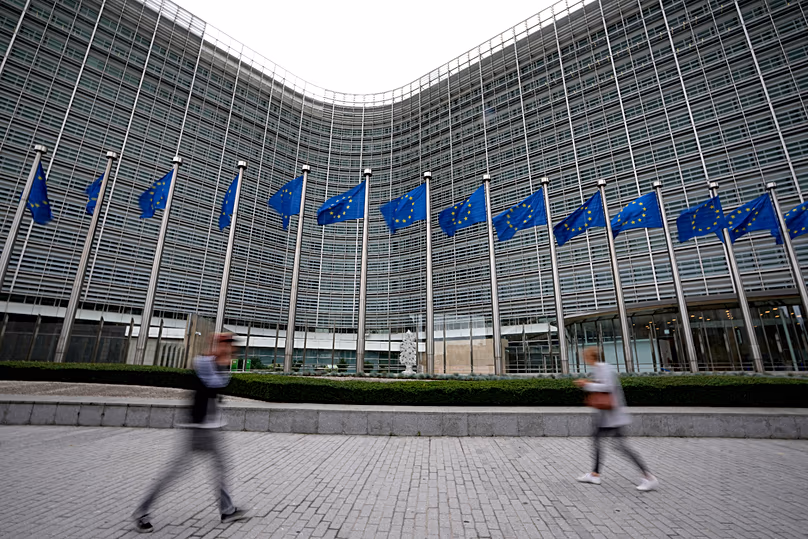 Les drapeaux de l’Union européenne flottent au vent tandis que des piétons passent devant le siège de l’UE à Bruxelles, le 20 septembre 2023.