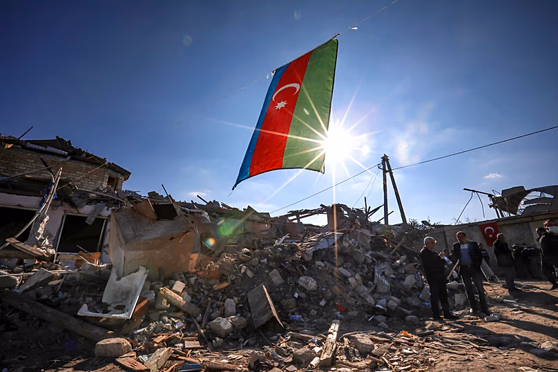 Le drapeau national de l'Azerbaïdjan flotte sur les maisons détruites dans une zone résidentielle touchée par des tirs de roquettes pendant la nuit par les forces arméniennes à Ganja, le 22 octobre 2020.