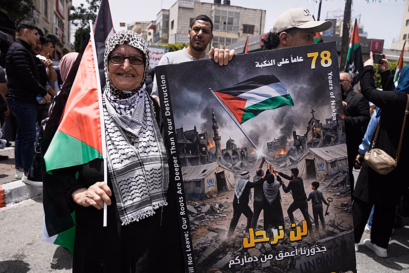 Une Palestinienne âgée tient une pancarte indiquant "Nous ne partirons pas. Nos racines sont plus profondes que votre destruction" lors d