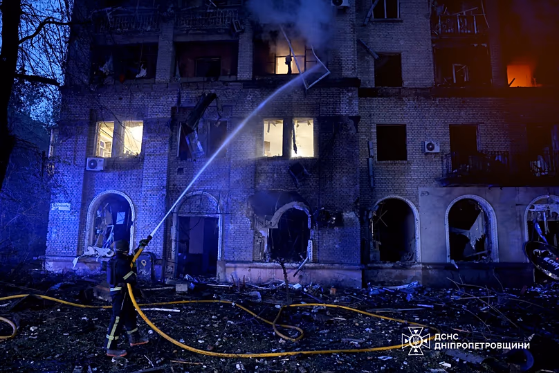 Des secouristes éteignent l'incendie d'un immeuble résidentiel endommagé après une grève russe à Dnipro, le 18 mai 2026.