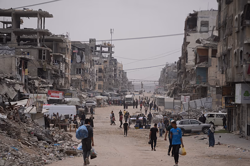 Des Palestiniens marchent le long d'une rue entourée de bâtiments détruits pendant la guerre du Hamas contre Israël, dans la ville de Gaza, le 15 mai 2026.