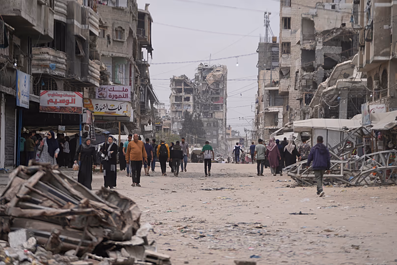 Des Palestiniens marchent le long d'une rue entourée de bâtiments détruits pendant la guerre du Hamas contre Israël, dans la ville de Gaza, le 15 mai 2026.