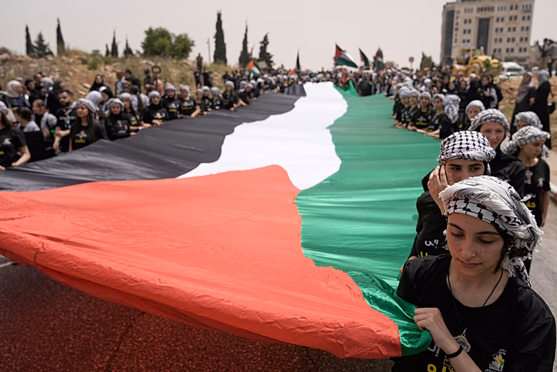 Des étudiants portent un grand drapeau palestinien lors d'un événement commémorant le 78e anniversaire de la Nakba à Ramallah, le 12 mai 2026.