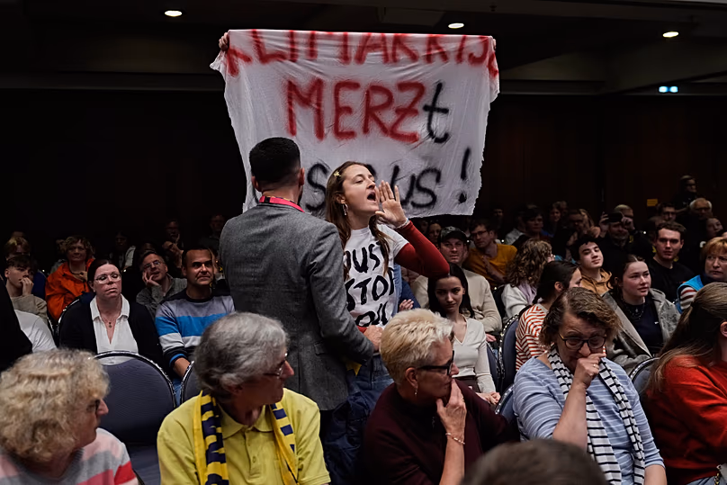 Une jeune femme proteste lors d'un discours du chancelier fédéral Friedrich Merz lors d'une table ronde à la Convention catholique allemande à Würzburg, le 15 mai 2026.