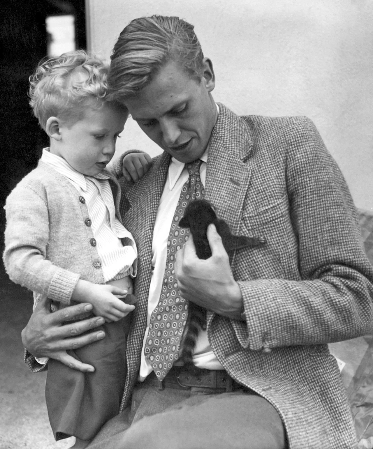 David Attenborough tient son fils Robert dans ses bras tout en regardant un coati-mundi, le 3 juin 1955.
