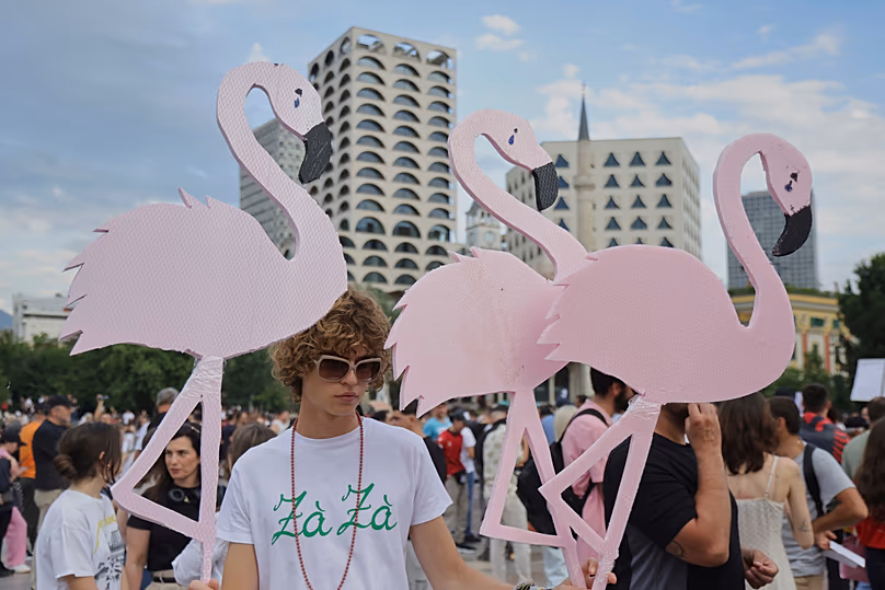 Des manifestants brandissent des découpes de flamants roses lors d'une manifestation à Tirana, le 3 juin 2026.