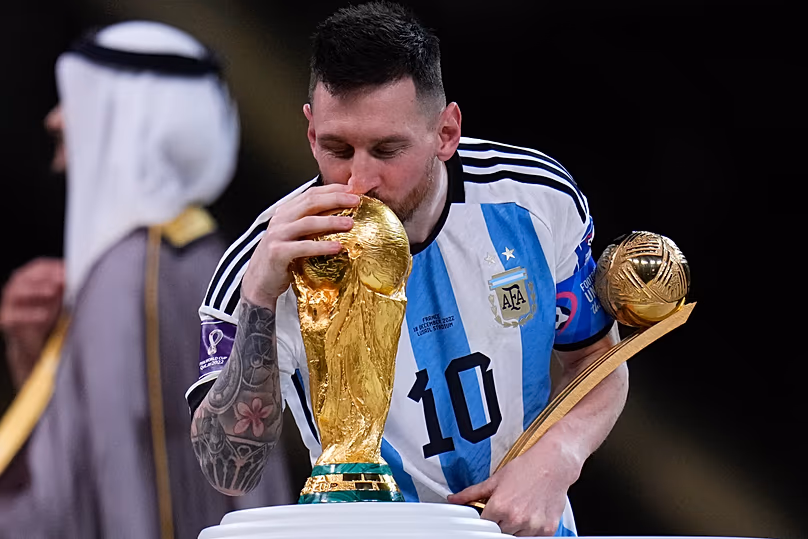 Lionel Messi embrasse le trophée tout en tenant le ballon d'or du meilleur joueur du tournoi après avoir remporté la finale de la Coupe du monde de football au stade Lusail de Lusail.