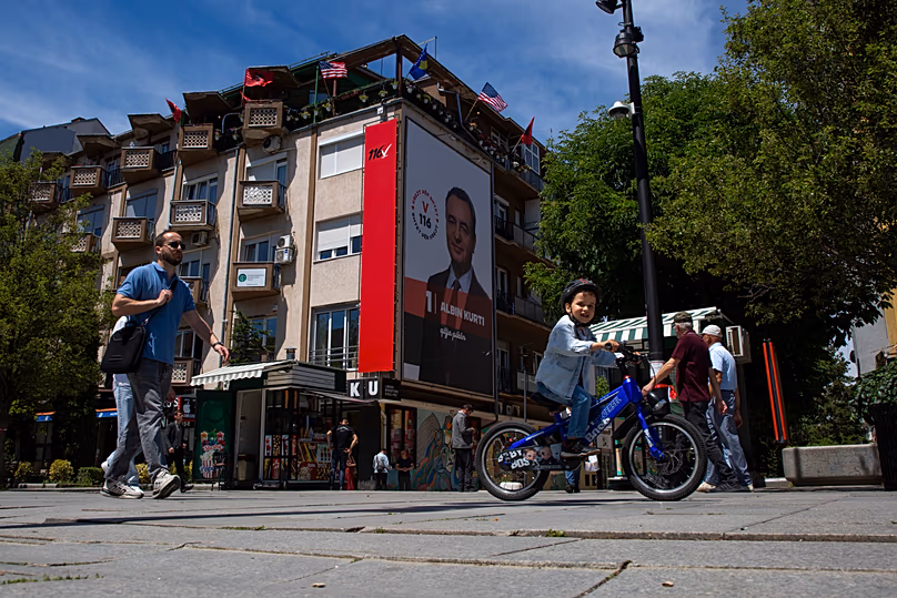 Des gens passent devant une affiche électorale géante du Premier ministre par intérim Albin Kurti à Pristina, le 5 juin 2026.